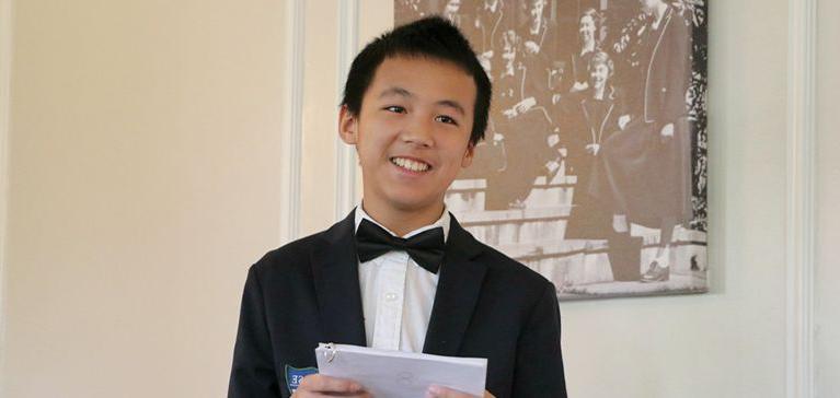 A young 887700葡京办理优惠大厅 student in a tuxedo gives a speech.