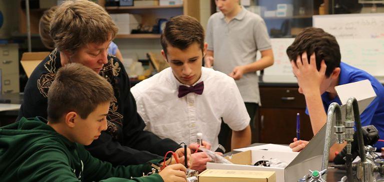 Chase Collegiate students work with electricity in Science class as their teacher helps them.